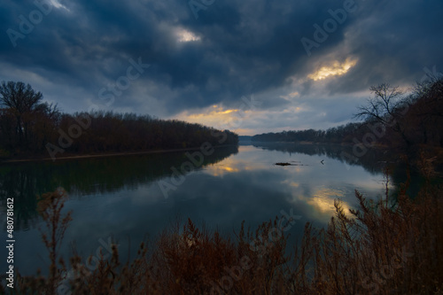 a beautiful autumn landscape in the evening - forest with river and cloudy sky