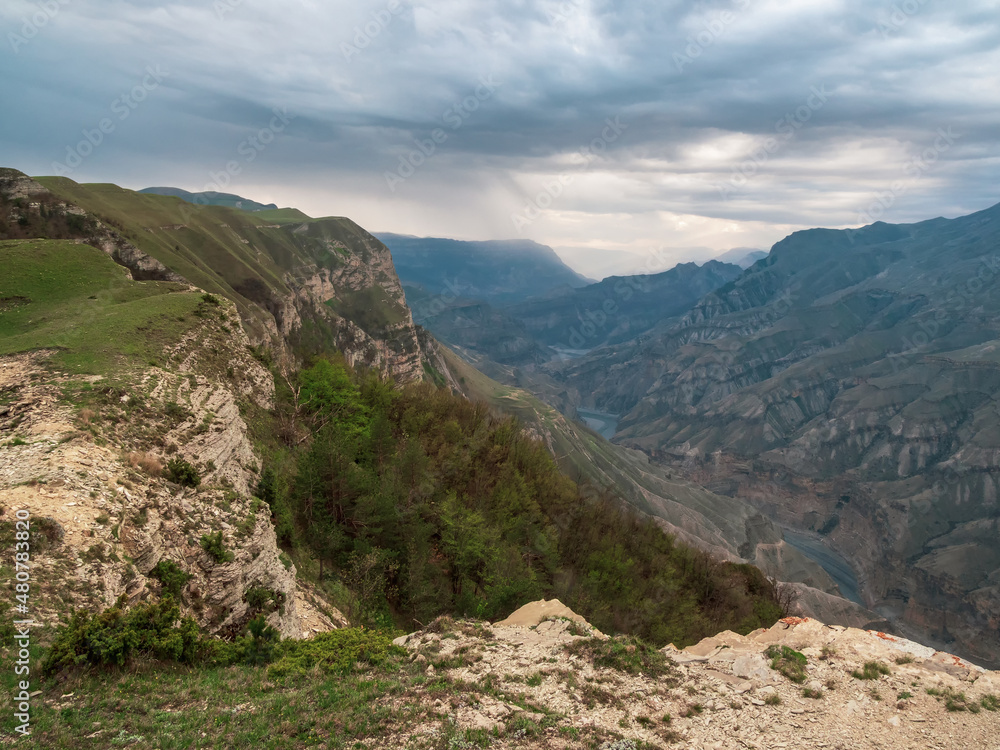 Colorful rainy landscape with cliff and big rocky mountains and epic deep gorge. High stone peaks of Dagestan mountains.