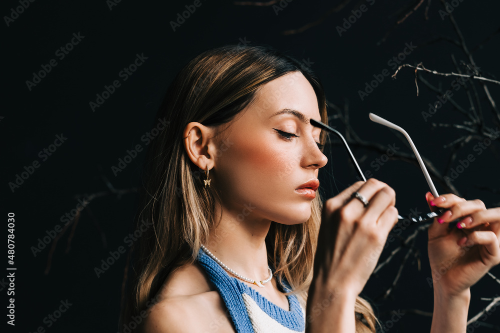 Fototapeta premium Young caucasian woman putting on eyeglasses.