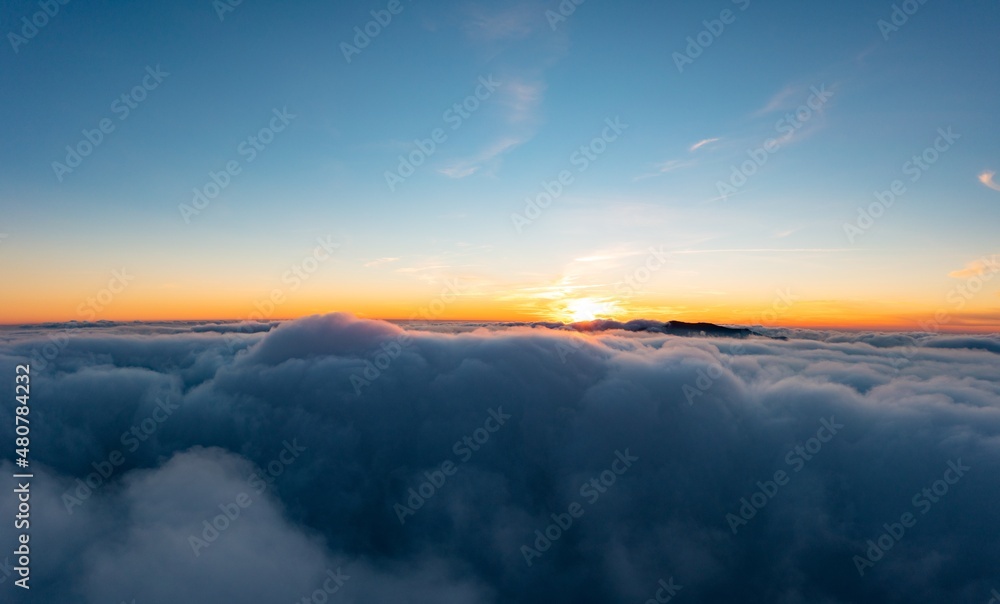 Thick layer of white clouds above mountains at sunrise