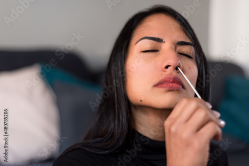 Detail portrait of woman performing an automatic COVID-19 test at home with Antigen kit. Introduction of nasal swab test for possible Coronavirus infection. Online medical and health-related services.