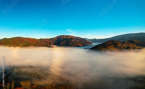 Thick layer of fog covering rainbow mountains with colorful trees