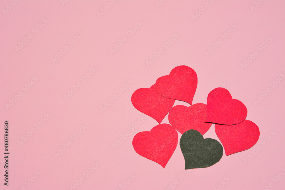 scarlet and black paper hearts on pink background, place for text