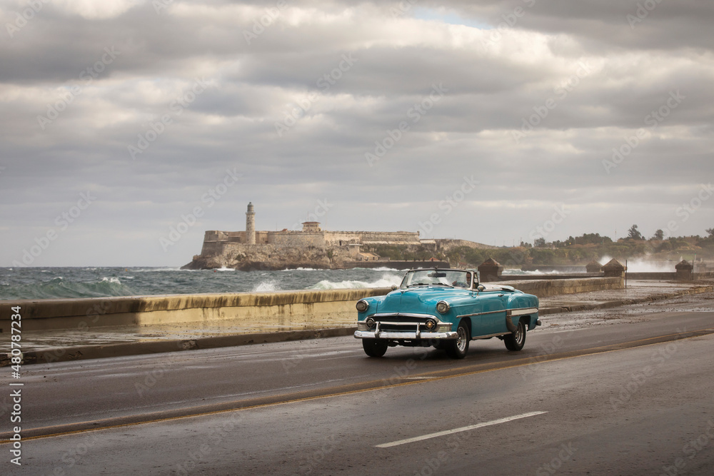 Old car on Malecon street of Havana with storm clouds in background. Cuba