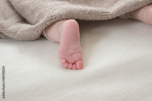 close up of small baby foot under knit blanket 