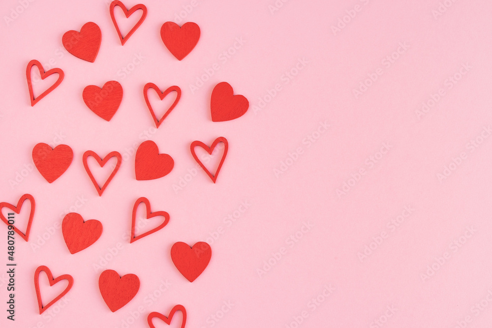 Red wooden hearts on a pink cardboard background. Copy space. Valentine's Day and Mother's Day.