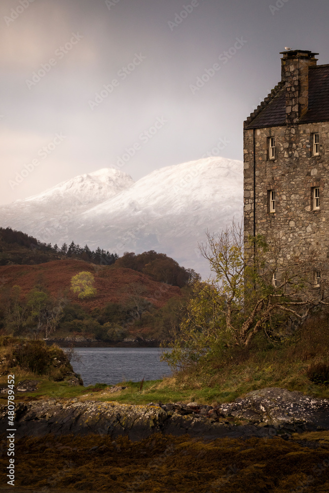 Eilean Donan Castle during colourful sunrise - Dornie, Scotland - United Kingdom. Mountains with snow in background.