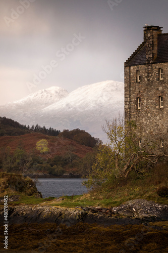 Eilean Donan Castle during colourful sunrise - Dornie, Scotland - United Kingdom. Mountains with snow in background.