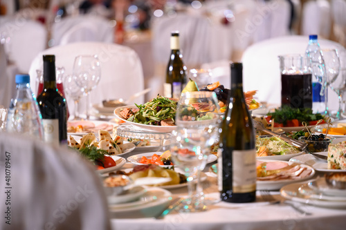 Plates with cold snack on table, cutlery for dinner, white napkin, selective focus.