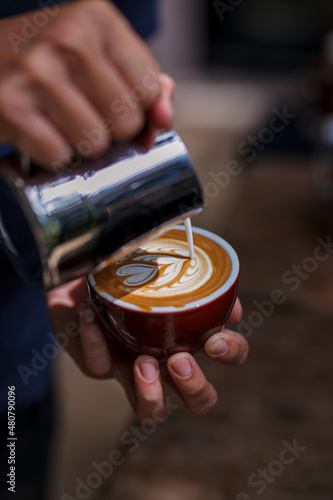 Barista making latte art  shot focus in cup of milk and coffee