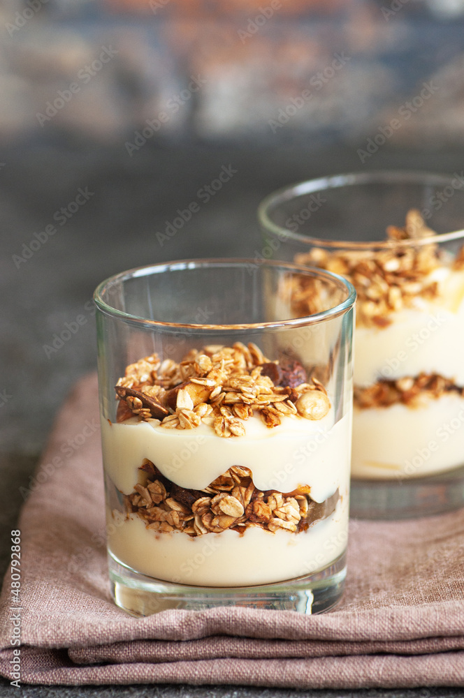 Granola with yogurt dessert in a glass. Gray background. Healthy eating or breakfast concept. Granola with yogurt dessert in a glass. Gray background. Healthy eating or breakfast concept.