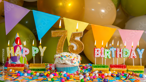 Creamy cupcake with candle for seventy five years, colorful happy birthday card for 75 year old, birthday cupcake with candles and birthday decorations..