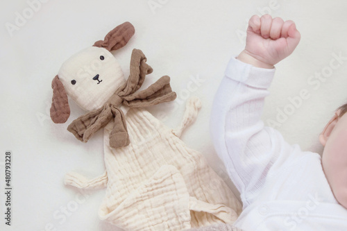 Photos baby lying in bed with soft muslin cuddly toy