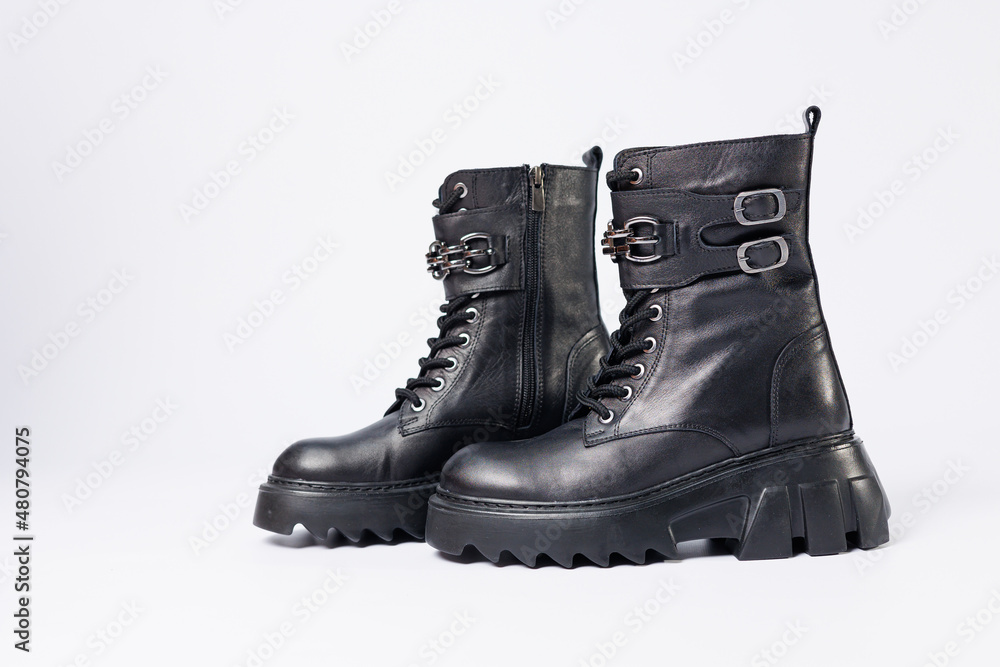 Women's shoes on a white background. Close-up of women's black leather boots with buckles on a white background. Shoes for the city. Concept for 2022 fashion, design and footwear.