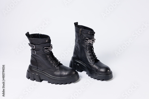 Women's shoes on a white background. Close-up of women's black leather boots with buckles on a white background. Shoes for the city. Concept for 2022 fashion, design and footwear.