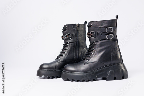 Women's shoes on a white background. Close-up of women's black leather boots with buckles on a white background. Shoes for the city. Concept for 2022 fashion, design and footwear.