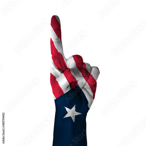 Hand pointing thumb up direction, liberia painted with flag as symbol of up direction, first and number one symbol - isolated on white background
