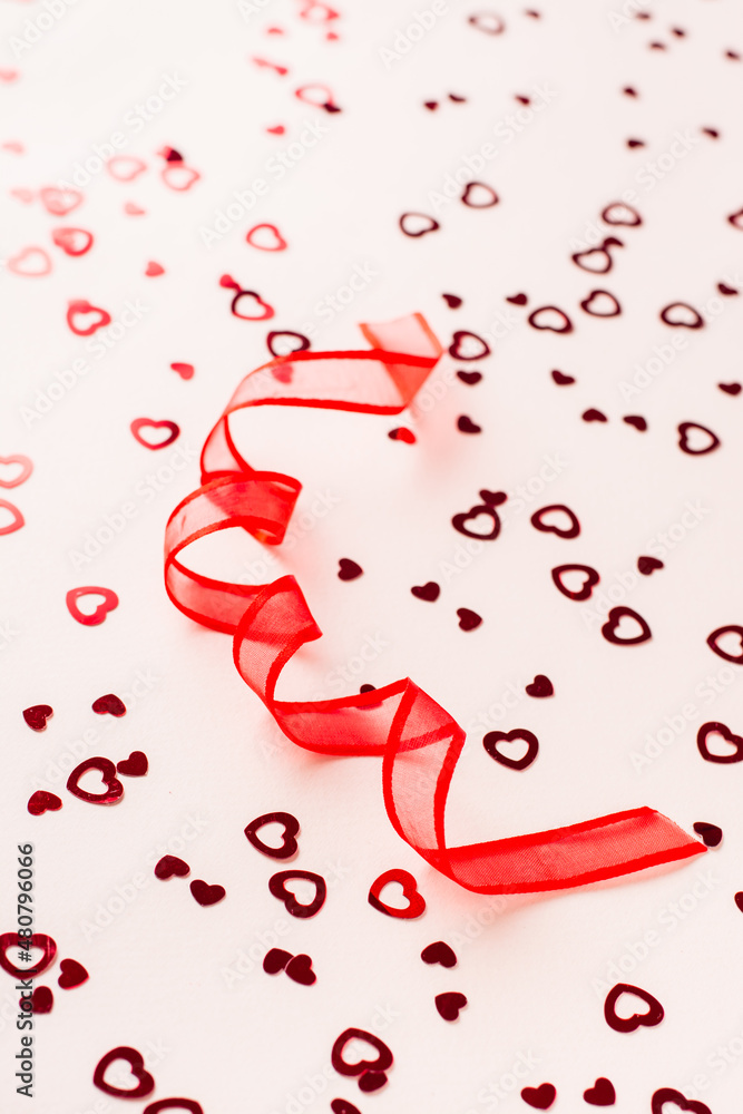 Valentine's Day. Red ribbon in the form of a spiral on a pink background with hearts. Vertical view Valentine's Day. Red ribbon in the form of a spiral on a pink background with hearts. Vertical view