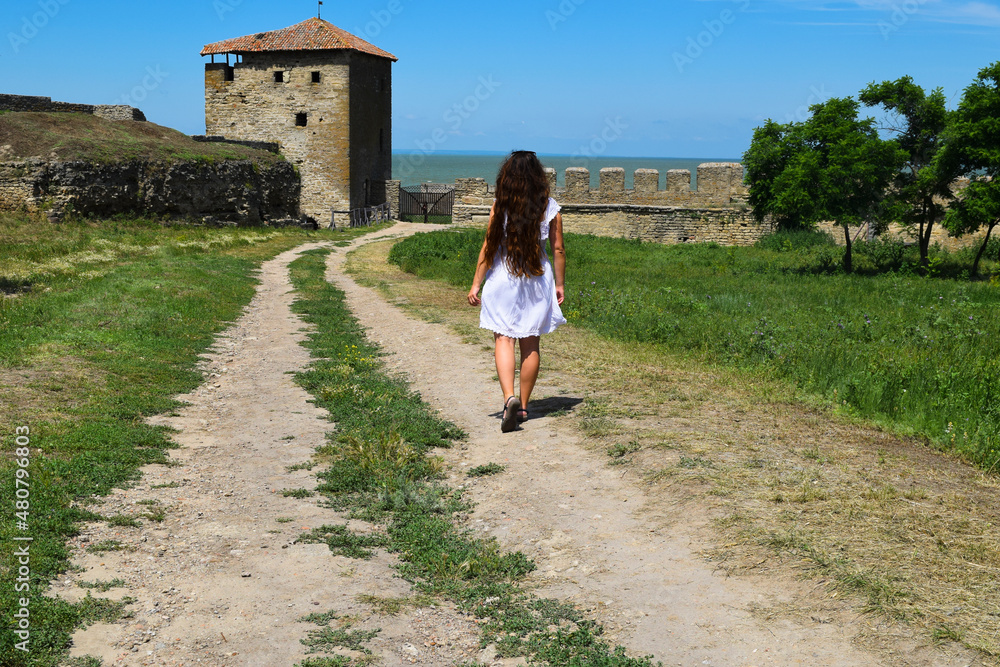 A girl in a beautiful white dress walks along a path in the ancient fortress Akerman, Belgorod-Dnestrovsky