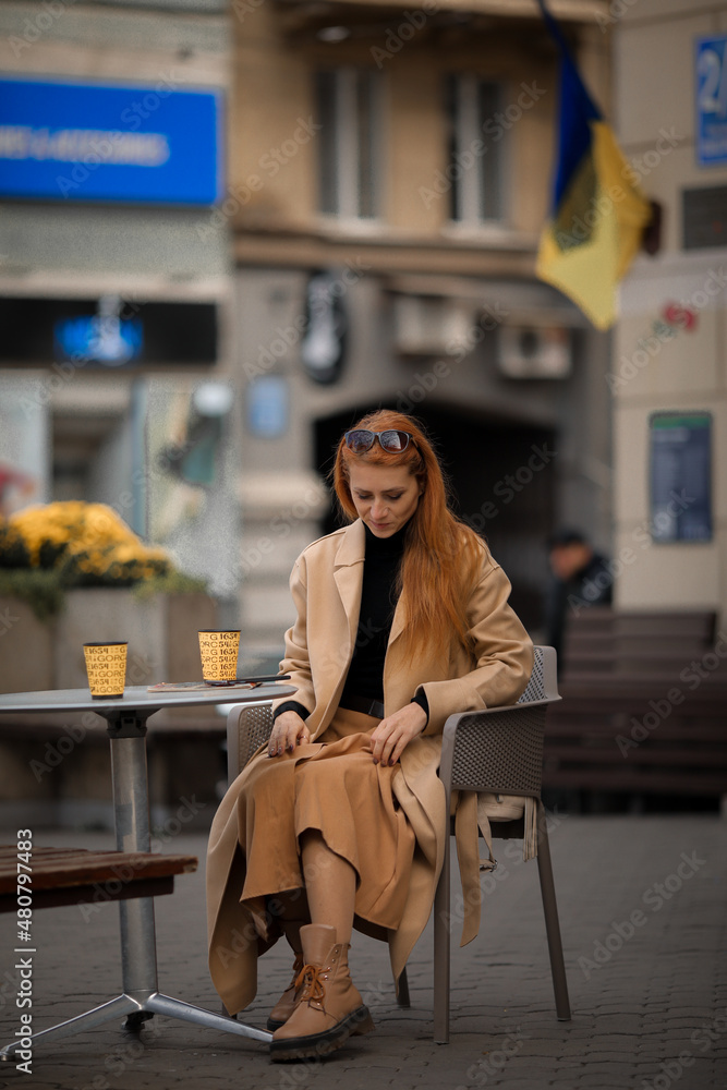 Obraz premium young red-haired woman drinking coffee in a cafe 