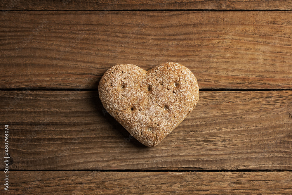 Freshly baked heart shaped bread. Single object on a wooden background. Top view, copy space. Freshly baked heart shaped bread. Single object on a wooden background. Top view, copy space.