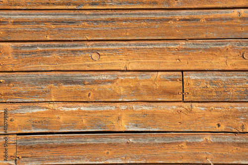..Orange flaky paint on a wooden old house wall. Plank texture background.