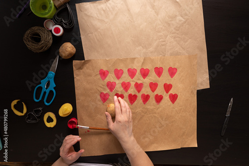 heart shaped potato stamp on craft paper. The process of decorating a gift for Valentine's Day. Getting ready for the celebration on February 14th.