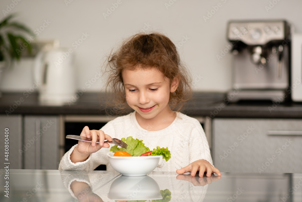 Two cute sisters' girls cut a salad from fresh vegetables. The girls are in the kitchen at home. They socialize and have fun while cooking. The concept of healthy eating. Healthy food. Childhood. Two cute sisters' girls cut a salad from fresh vegetables. The girls are in the kitchen at home. They socialize and have fun while cooking. The concept of healthy eating. Healthy food. Childhood.