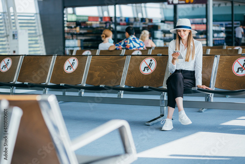 Teenage girl is using a smartphone to check flight at the international airport to travel on weekends