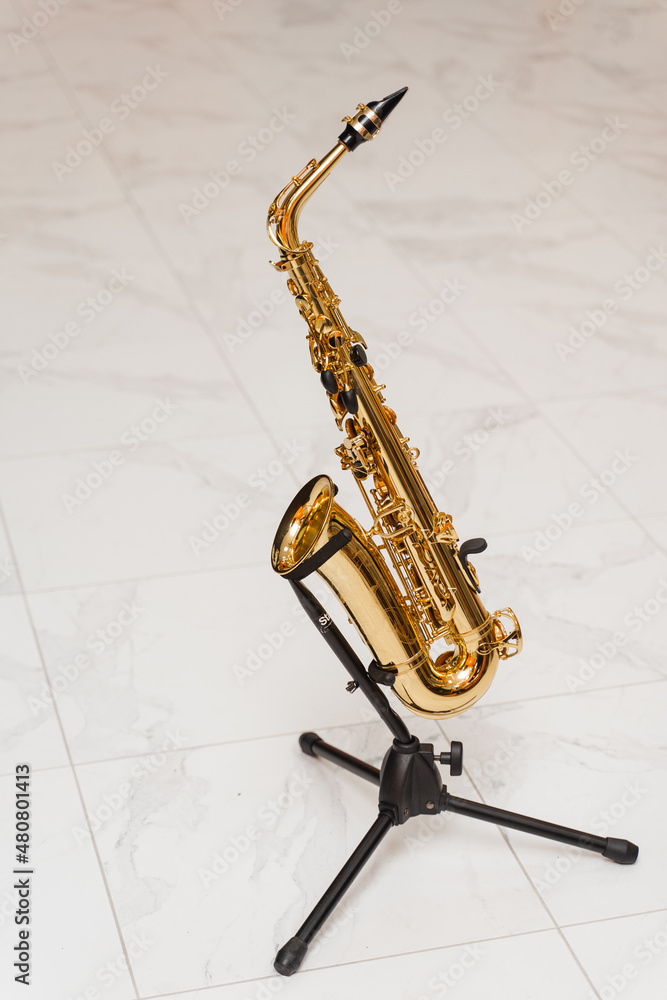 Naklejka premium Saxophone musician instrument on stand on white background. Sax musical instrument for play jazz.