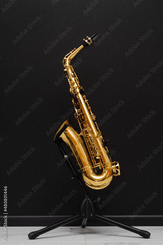 Naklejka premium Sax musical instrument for play jazz. Saxophone musician instrument on stand on black background.