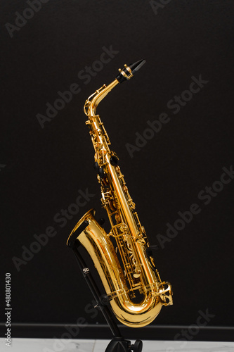 Saxophone musician instrument on stand on black background. Sax musical instrument for play jazz.