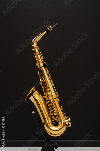 Saxophone musician instrument on stand on black background. Sax musical instrument for play jazz.