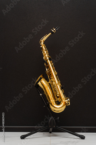 Sax musical instrument for play jazz. Saxophone musician instrument on stand on black background.