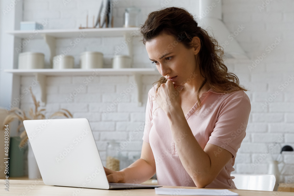 Thoughtful millennial woman looking at computer screen, checking email, web surfing information, making decisions working on online freelance project, considering problem solution or creating ideas. Thoughtful millennial woman looking at computer screen, checking email, web surfing information, making decisions working on online freelance project, considering problem solution or creating ideas.