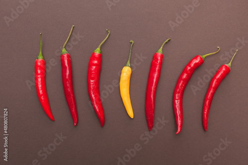 red and yellow chili peppers isolated on brown background