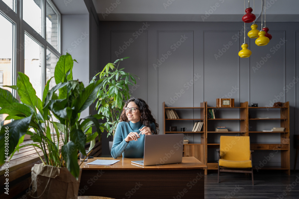 Φωτογραφία Happy freelancer woman relaxing from work in coworking space or library dreamy looking in window after successful video conference meeting with client, employer or team leader