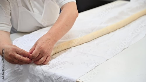 Cook working with rolled dough with filling for placints, Romanian and Moldovan traditional food. Slow motion photo