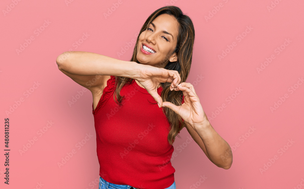 Young hispanic woman wearing casual clothes smiling in love doing heart symbol shape with hands. romantic concept. Young hispanic woman wearing casual clothes smiling in love doing heart symbol shape with hands. romantic concept.