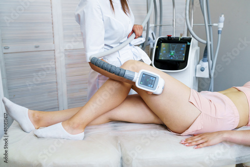 Woman receiving treatment for cellulite. Slimming vacuum massage machine. Vacuum massage of the buttocks and legs. Anti-cellulite body shaping procedure. Young woman and doctor in medicine salon