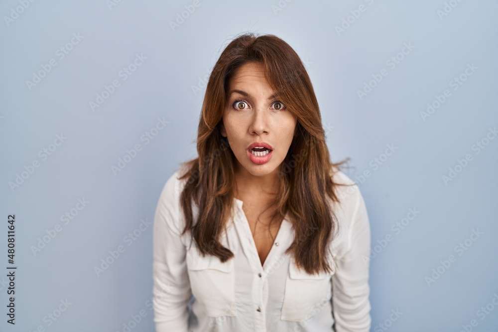 Hispanic woman standing over isolated background afraid and shocked with surprise and amazed expression, fear and excited face. Hispanic woman standing over isolated background afraid and shocked with surprise and amazed expression, fear and excited face.
