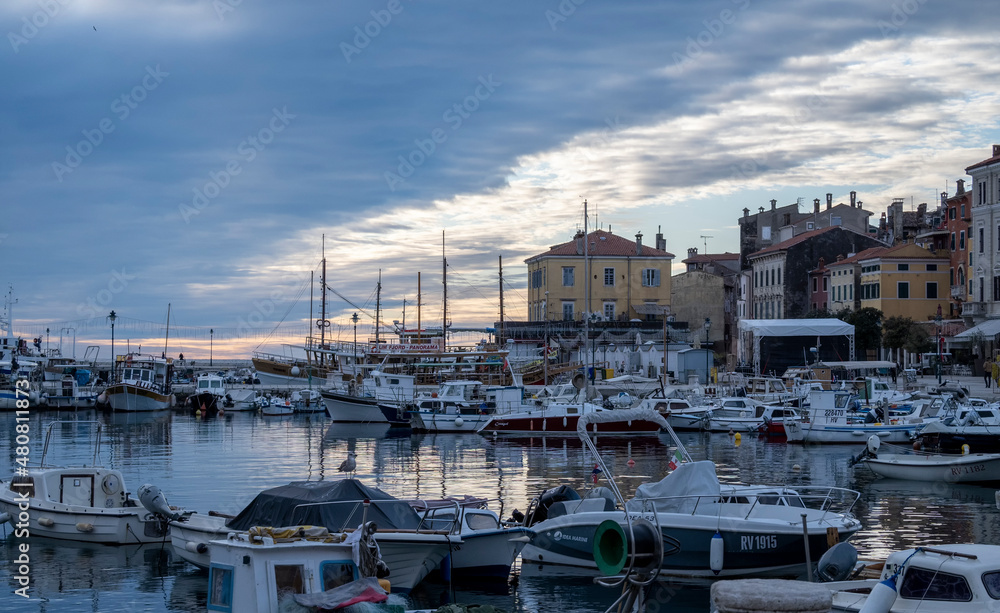 Anchored sailing boats in the Rovinj city port, during winter sunset