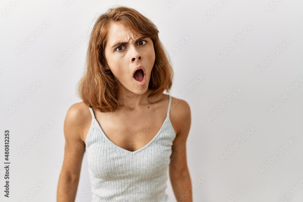 Beautiful caucasian woman standing over isolated background in shock face, looking skeptical and sarcastic, surprised with open mouth Beautiful caucasian woman standing over isolated background in shock face, looking skeptical and sarcastic, surprised with open mouth