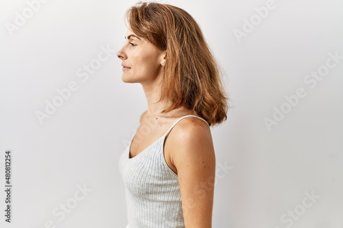 Beautiful caucasian woman standing over isolated background looking to side, relax profile pose with natural face and confident smile.
