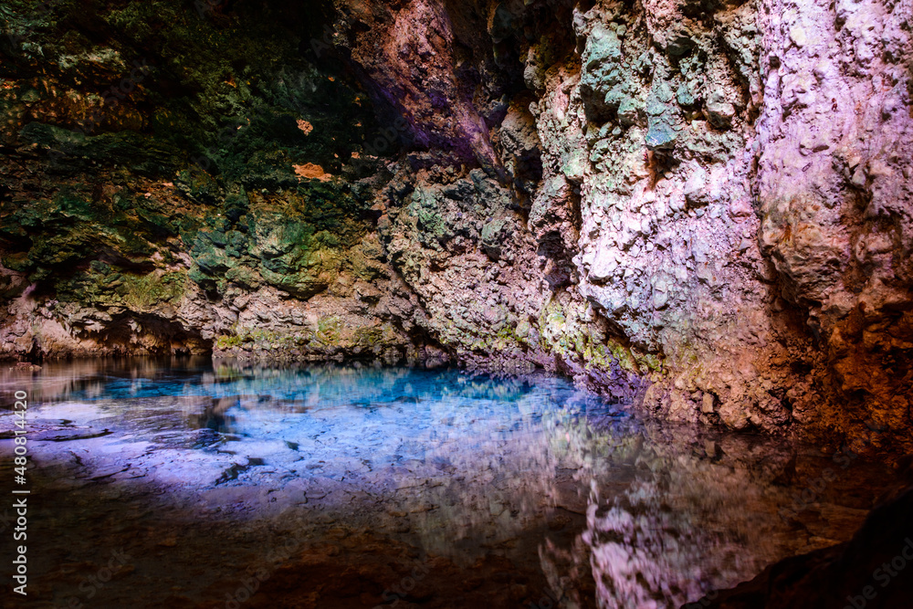 Stalactites and stalagmites in a Kuza cave at Zanzibar, Tanzania. Natural pool with crystal clear water