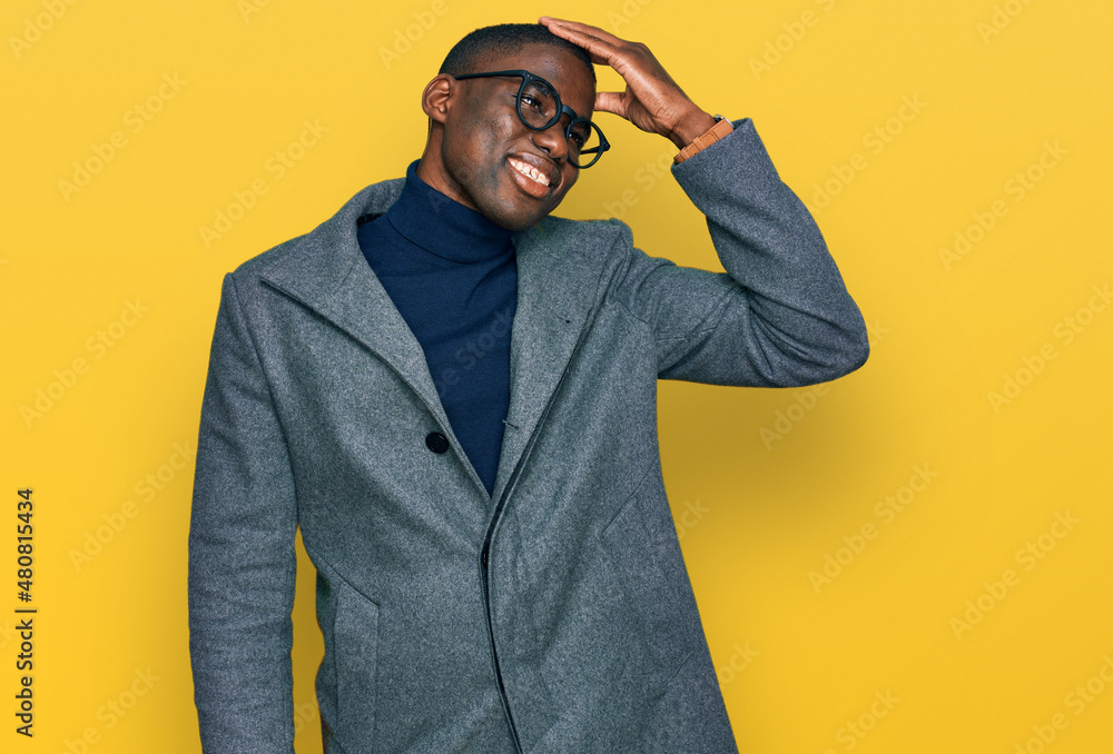 Young african american man wearing business clothes and glasses smiling confident touching hair with hand up gesture, posing attractive and fashionable Young african american man wearing business clothes and glasses smiling confident touching hair with hand up gesture, posing attractive and fashionable