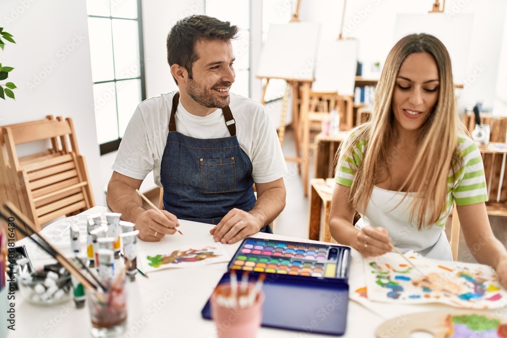 Fototapeta premium Two students smiling happy painting sitting on the table at art school.