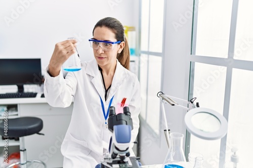 Young hispanic woman wearing scientist uniform holding test tube at laboratory