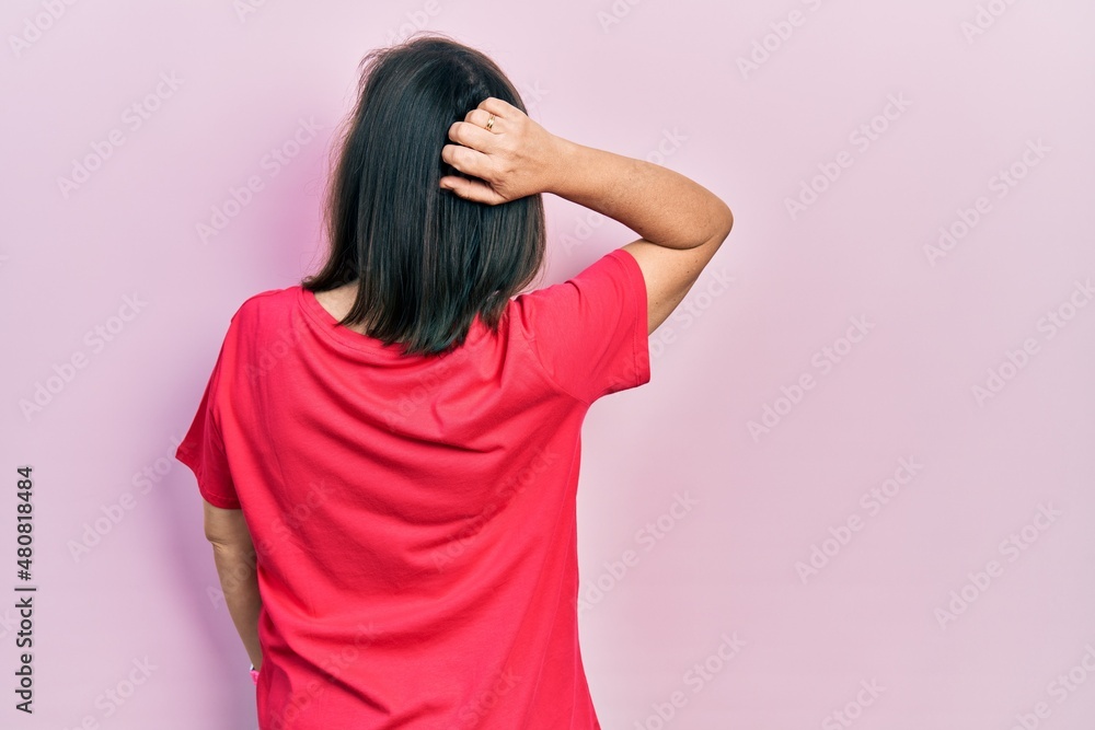 Middle age hispanic woman wearing casual clothes backwards thinking about doubt with hand on head Middle age hispanic woman wearing casual clothes backwards thinking about doubt with hand on head