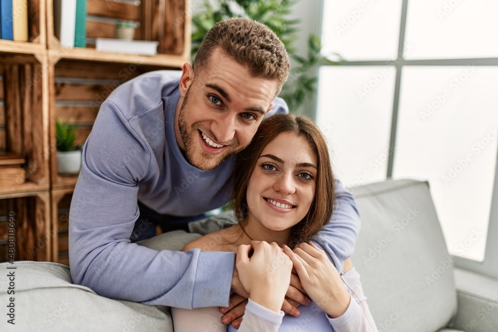 Young caucasian couple sitting on the sofa hugging at home. Young caucasian couple sitting on the sofa hugging at home.